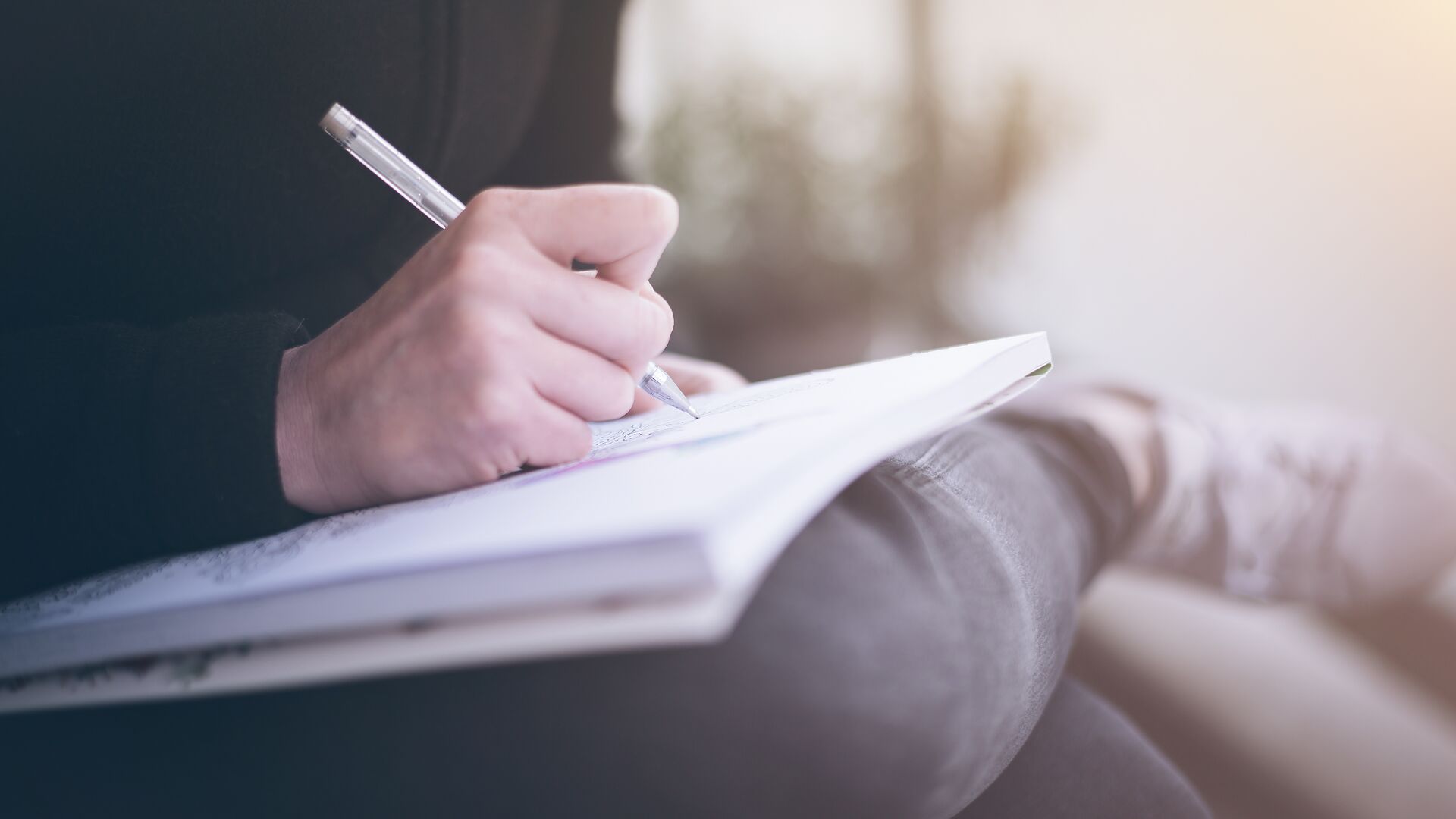 Writing woman writing or scribbling on a notepad that is resting on her legs