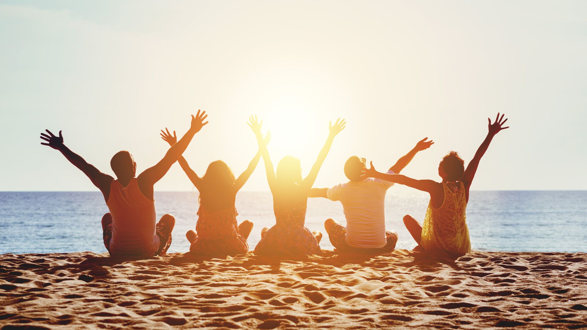 Group on Beach Group of five happy people sits on background of empty sunset beach. Travel or sea vacations concept